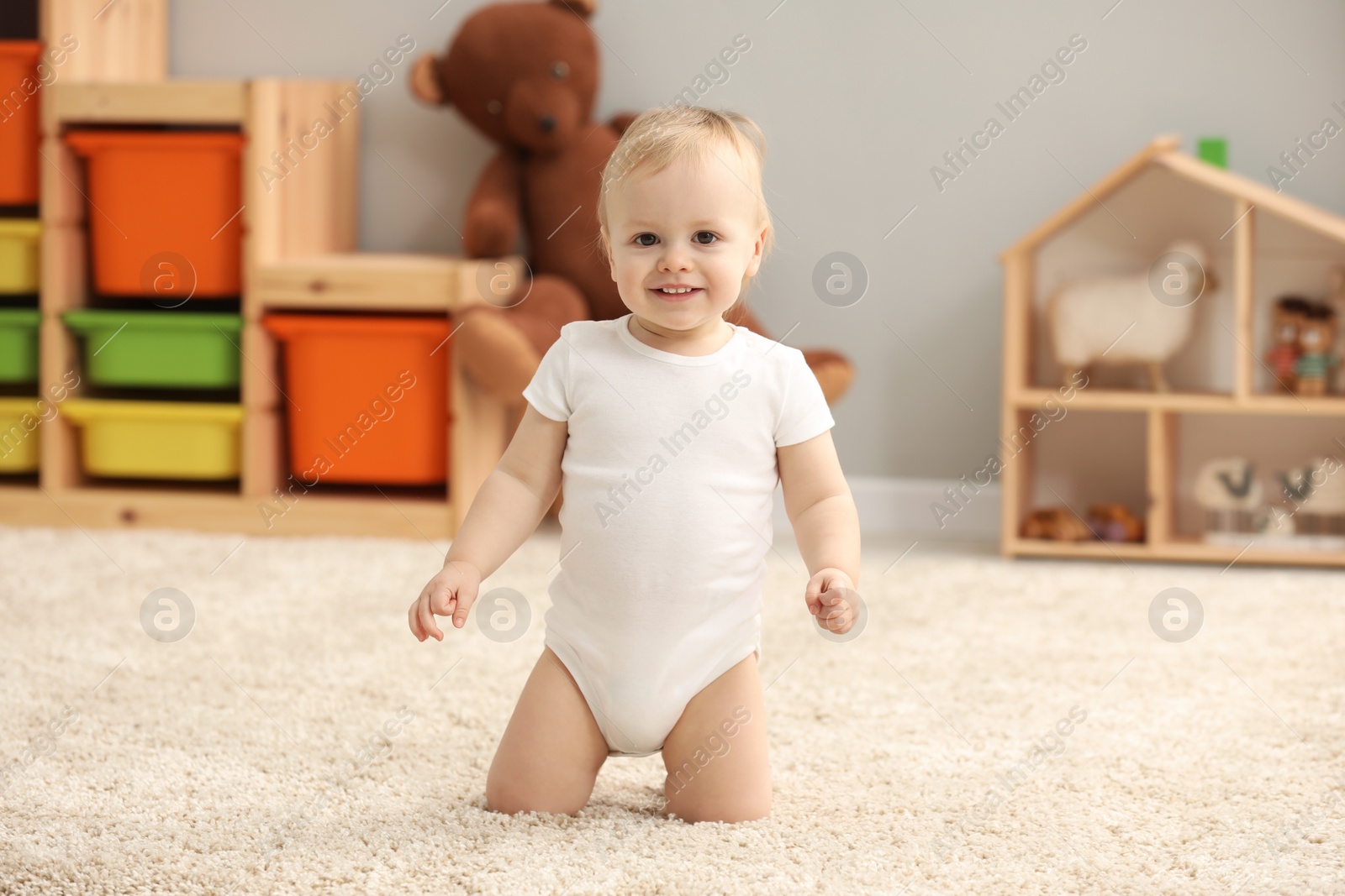 Photo of Cute little boy on rug in children's room