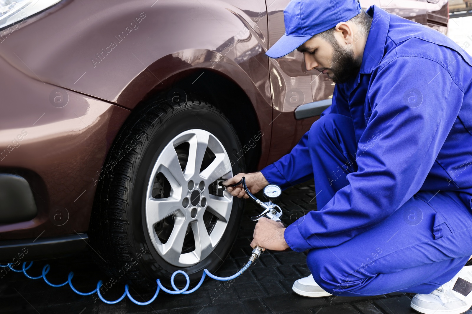 Photo of Mechanic checking tire air pressure at car service
