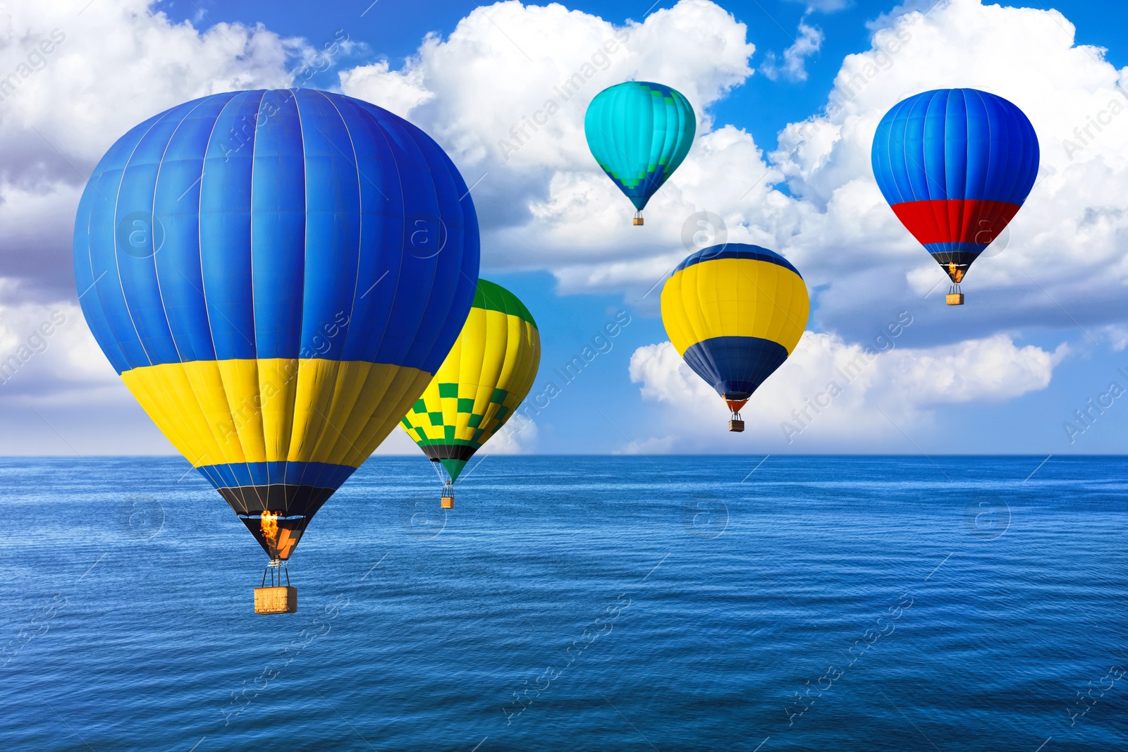 Image of Bright hot air balloons flying over blue sea