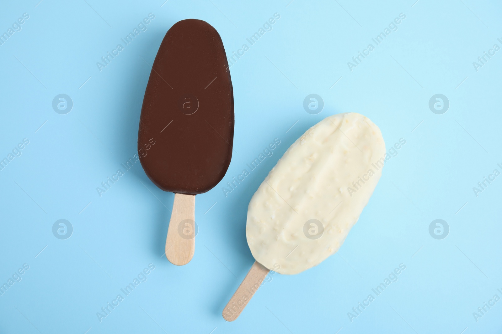 Photo of Glazed ice cream bars on light blue background, flat lay