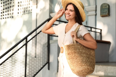 Young woman with stylish straw bag outdoors