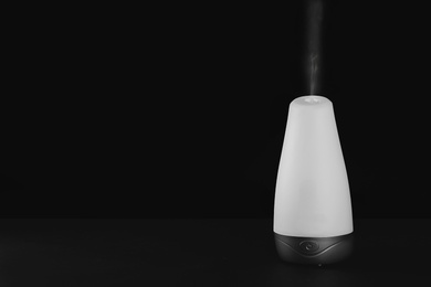 Photo of Aroma oil diffuser on black background. Air freshening