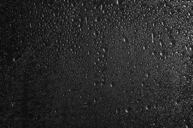 Photo of Glass with rain drops against dark background