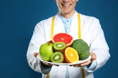 Photo of Nutritionist with healthy products on blue background, closeup