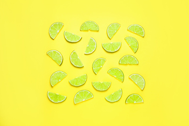 Photo of Juicy fresh lime slices on yellow background, flat lay