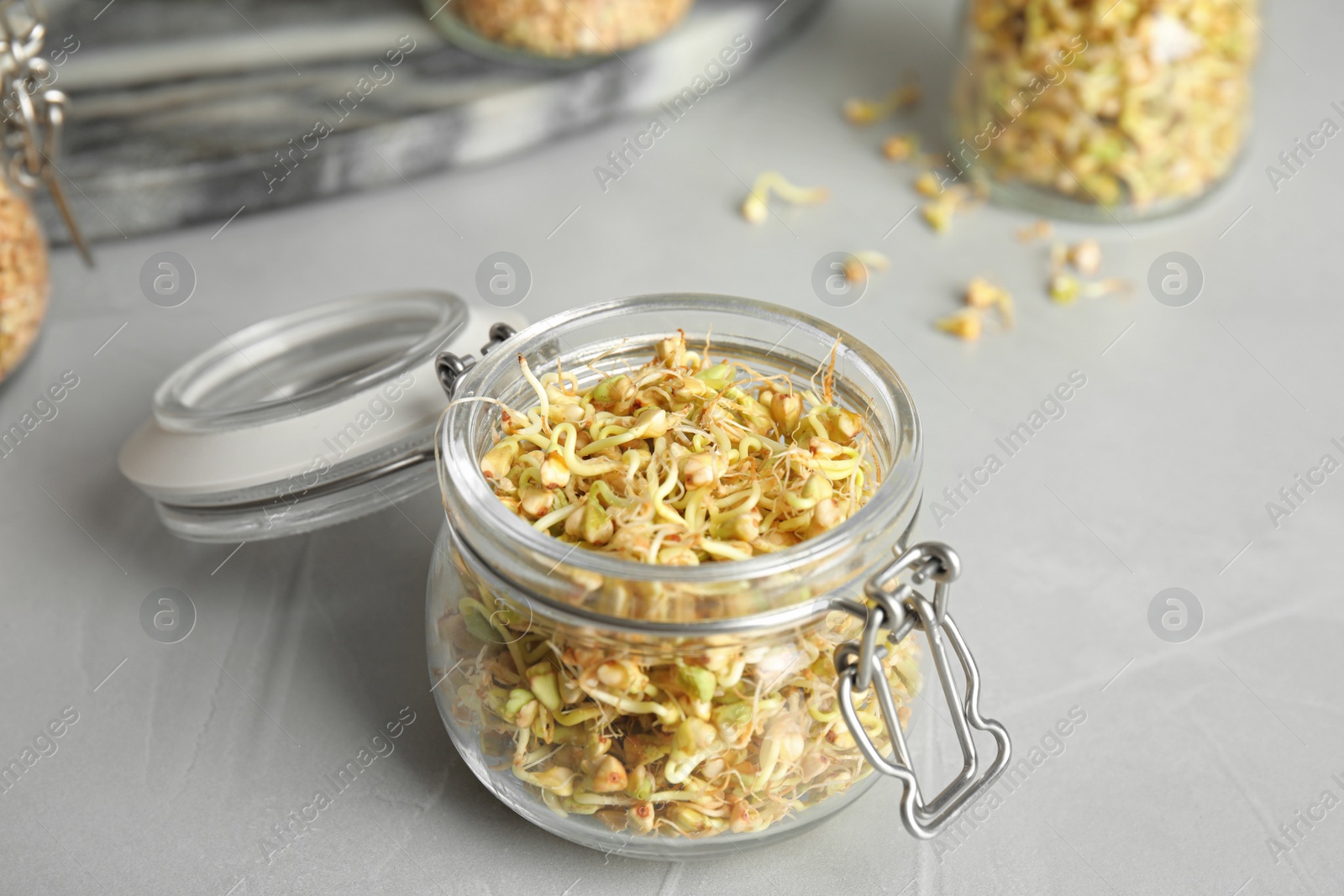 Photo of Glass jar of sprouted green buckwheat on light grey table