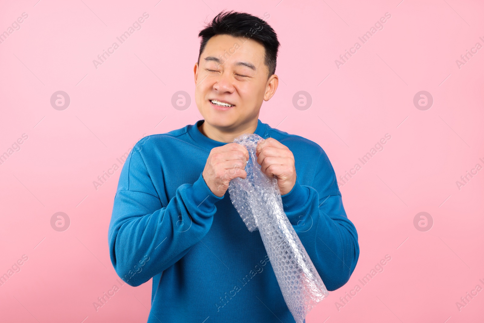 Photo of Asian man with bubble wrap on pink background