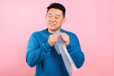 Asian man with bubble wrap on pink background