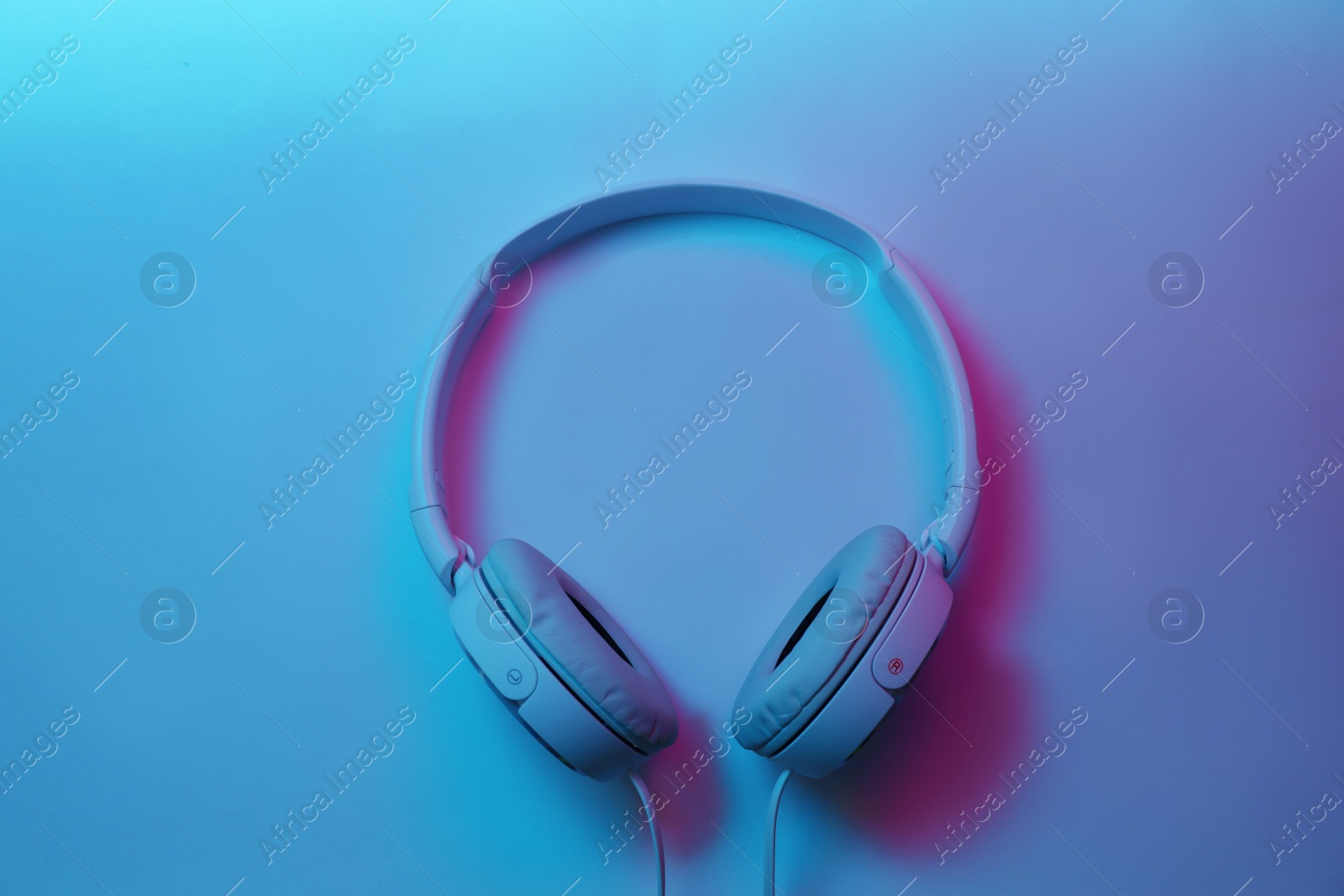 Photo of Stylish modern headphones with earmuffs on color background, top view