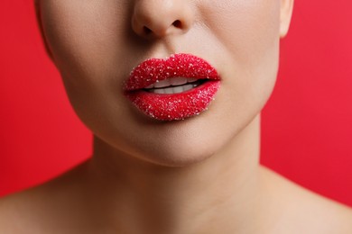 Closeup view of woman with lips covered in sugar on red background