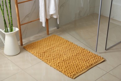 Photo of Soft orange bath mat on floor indoors