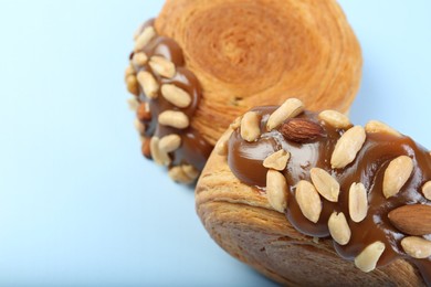 Tasty puff pastry. Supreme croissants with chocolate paste and nuts on light blue background, above view. Space for text