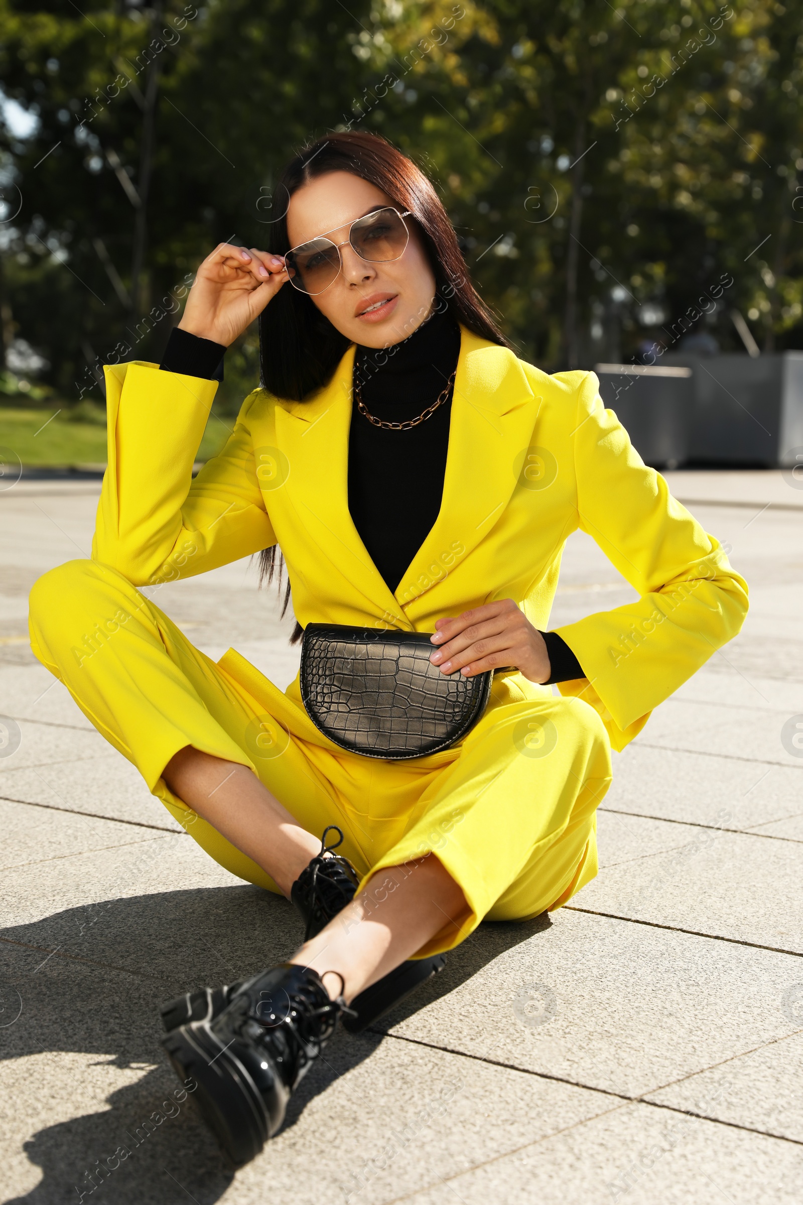 Photo of Beautiful young woman with stylish waist bag on city street