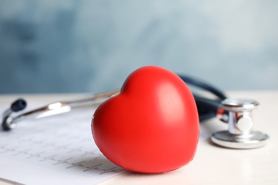 Stethoscope, red heart and cardiogram on table. Cardiology concept