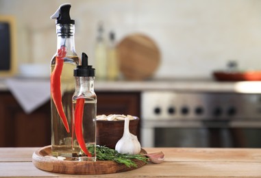 Bottles of cooking oil and ingredients on wooden table in kitchen, space for text