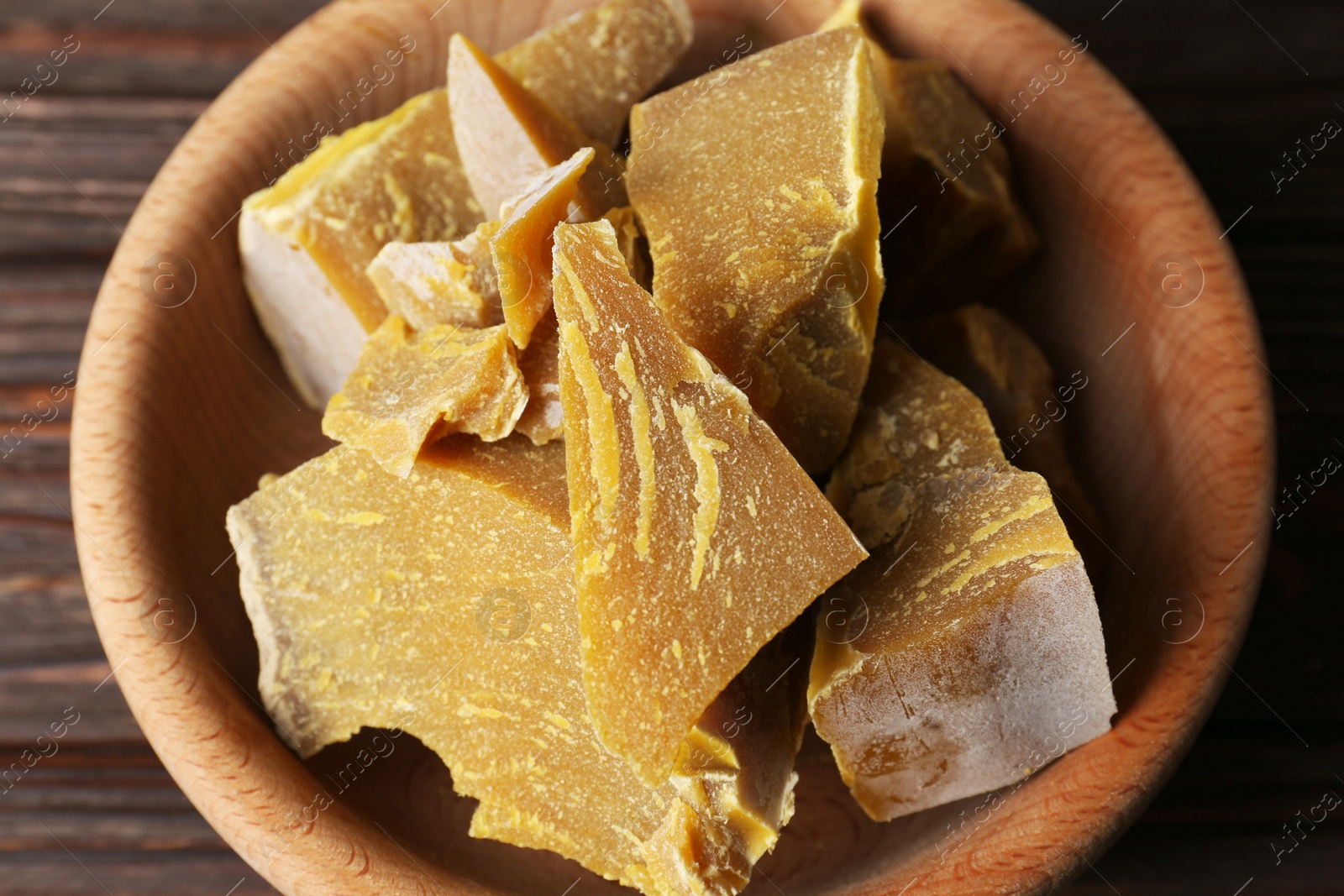 Photo of Bowl with natural beeswax blocks on wooden table, above view