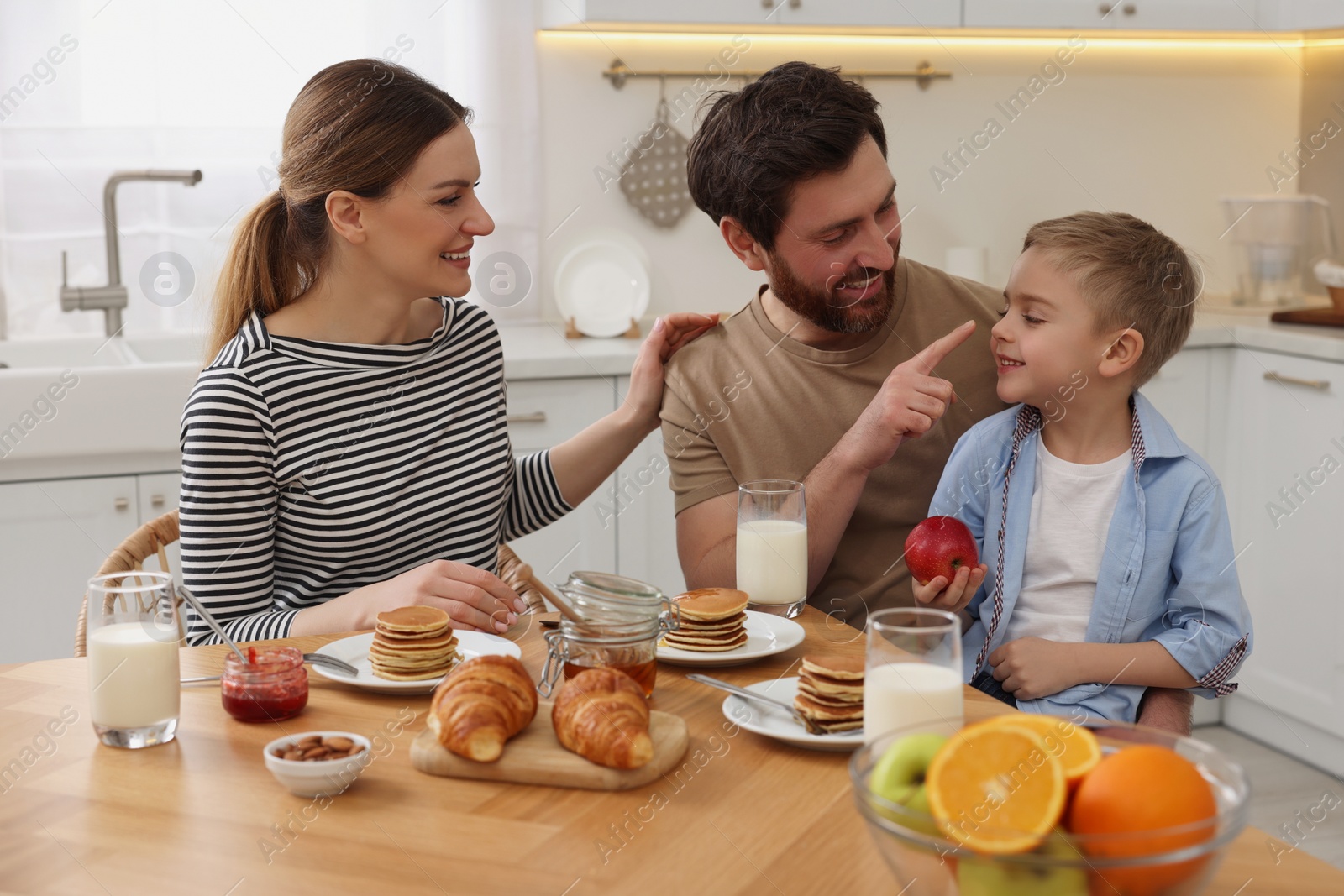 Photo of Happy family having fun during breakfast at table in kitchen