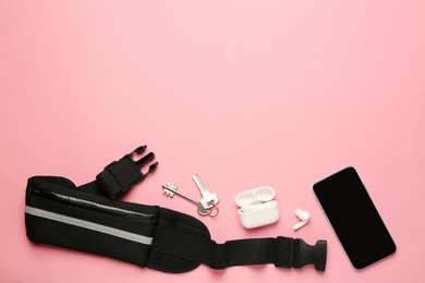 Flat lay composition with stylish black waist bag on pink background, space for text