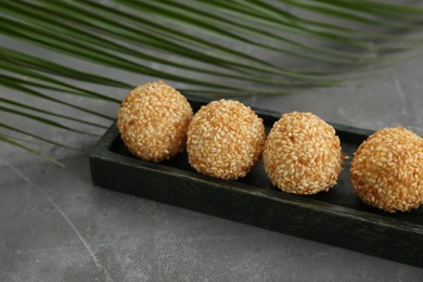 Photo of Delicious sesame balls and green leaf on grey table