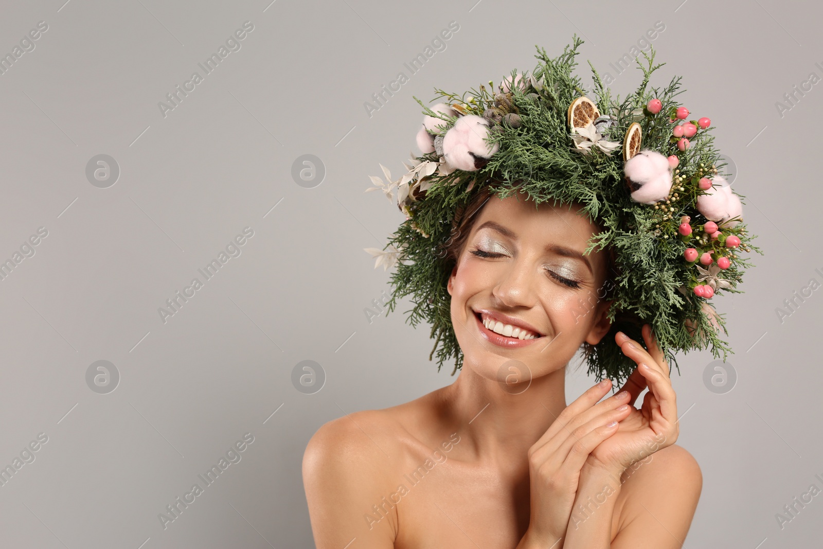 Photo of Happy young woman wearing wreath on grey background. Space for text