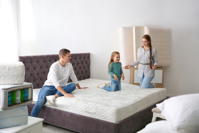 Photo of Happy family choosing mattress in furniture store
