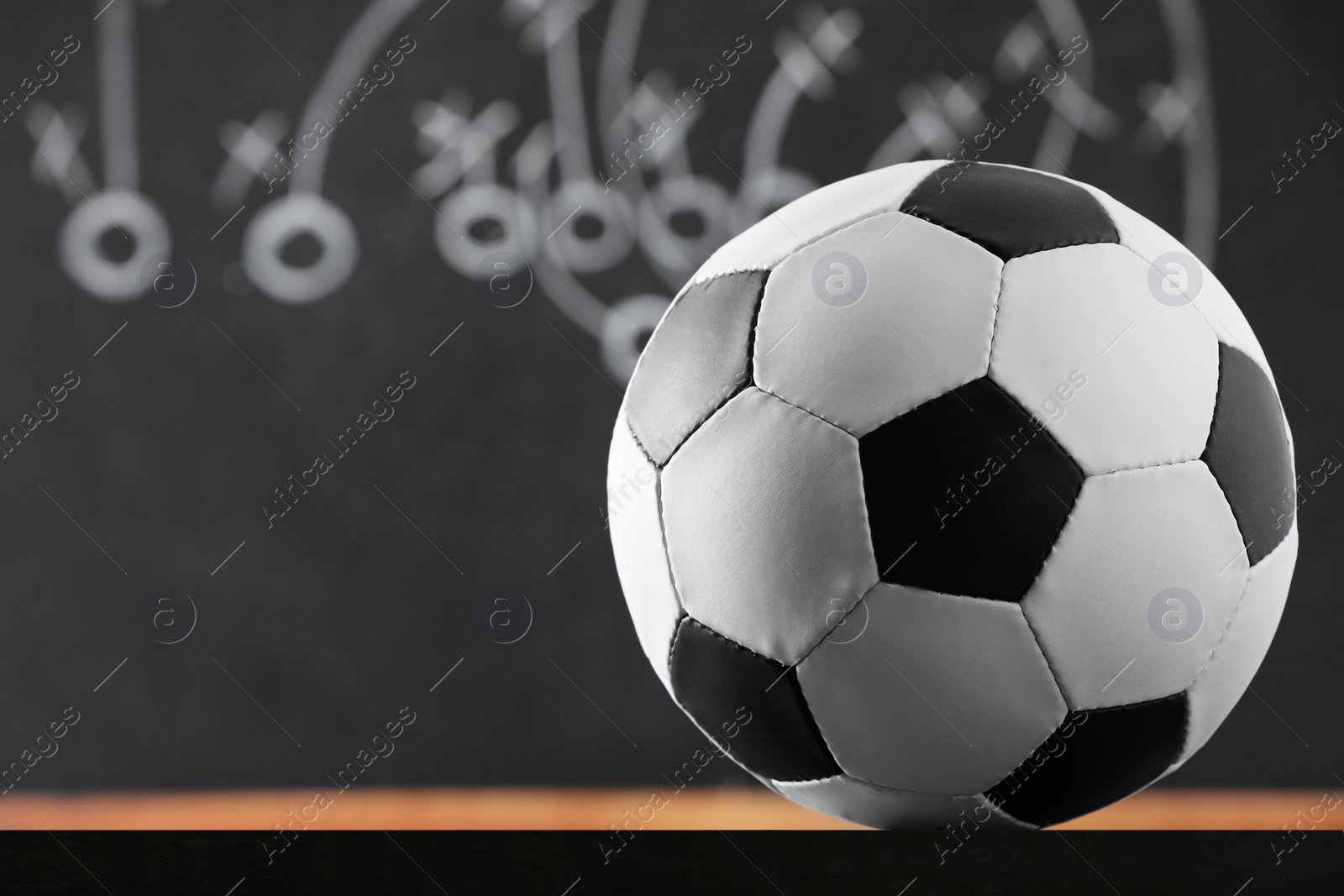 Photo of Football ball against blurred game scheme. Space for text