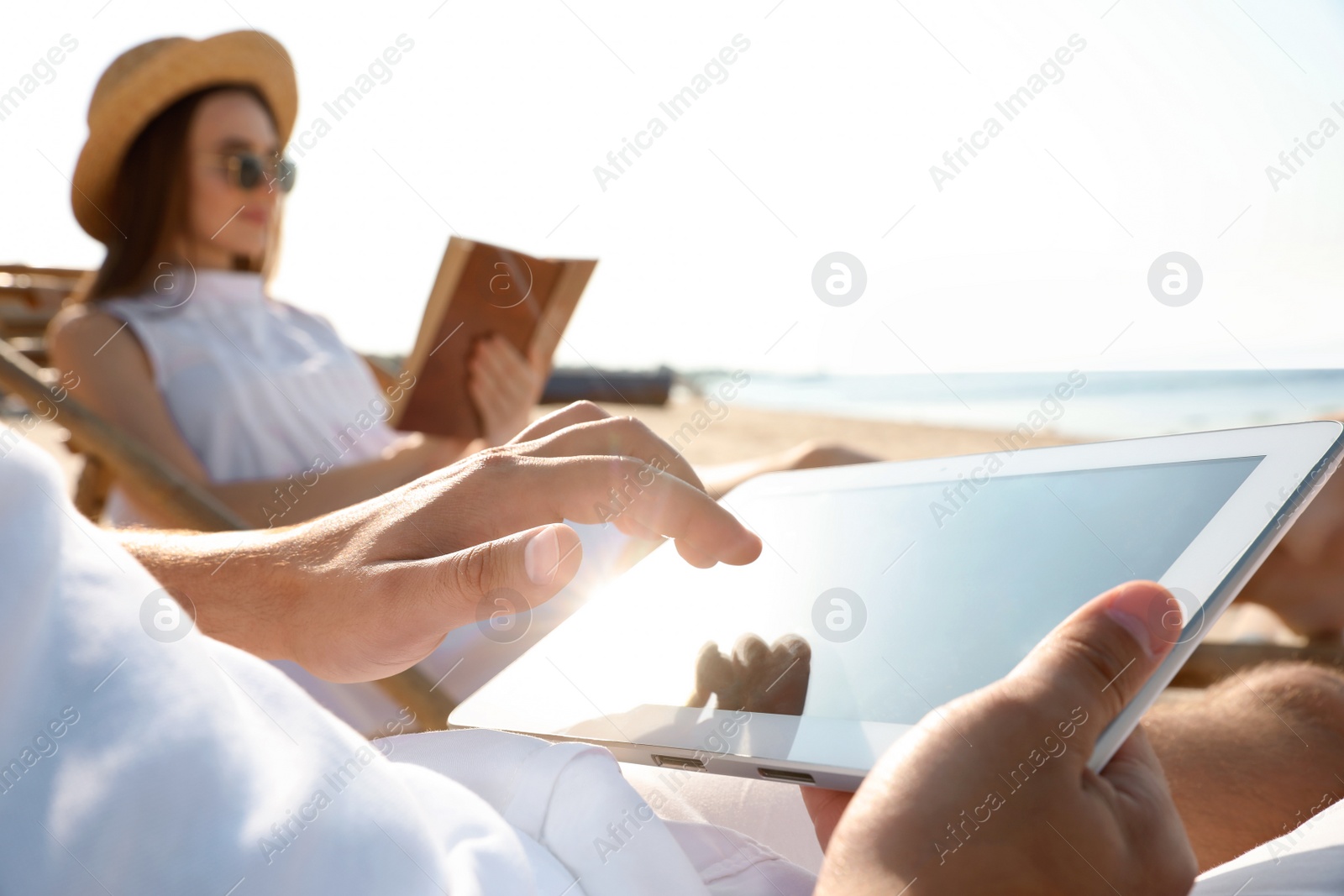 Photo of Young couple relaxing in deck chairs on sandy beach