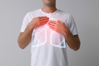 Man holding hands near chest with illustration of lungs on grey background, closeup