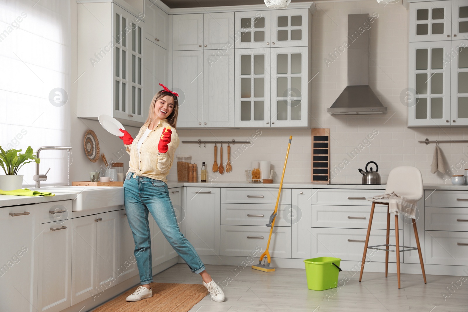 Photo of Woman singing while washing dishes in kitchen