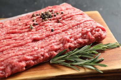 Photo of Raw ground meat, rosemary and peppercorns on table, closeup