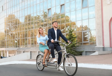 Photo of Couple riding tandem bike on city street