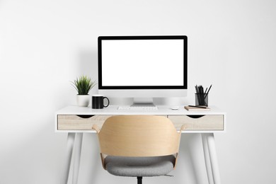 Photo of Cozy workspace with computer, houseplant and stationery on wooden desk at home