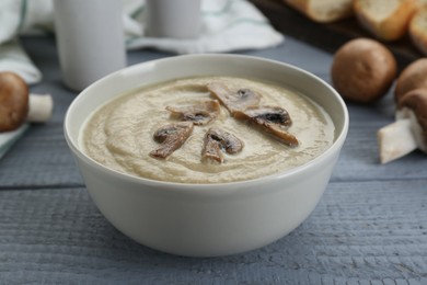 Photo of Delicious mushroom cream soup on light grey wooden table, closeup