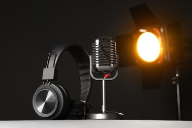 Photo of Vintage microphone and headphones on table against black background. Sound recording and reinforcement