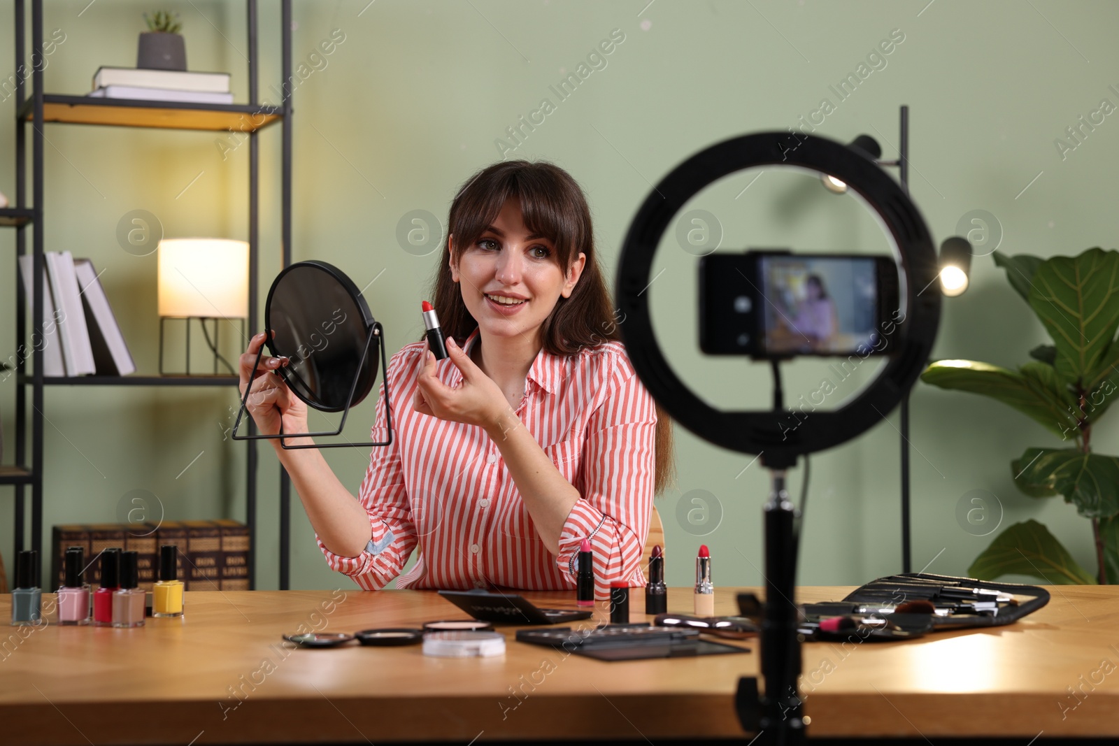 Photo of Smiling beauty blogger recording makeup tutorial at home