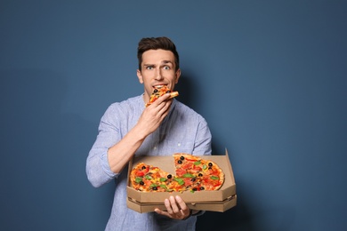 Attractive young man with delicious pizza on color background