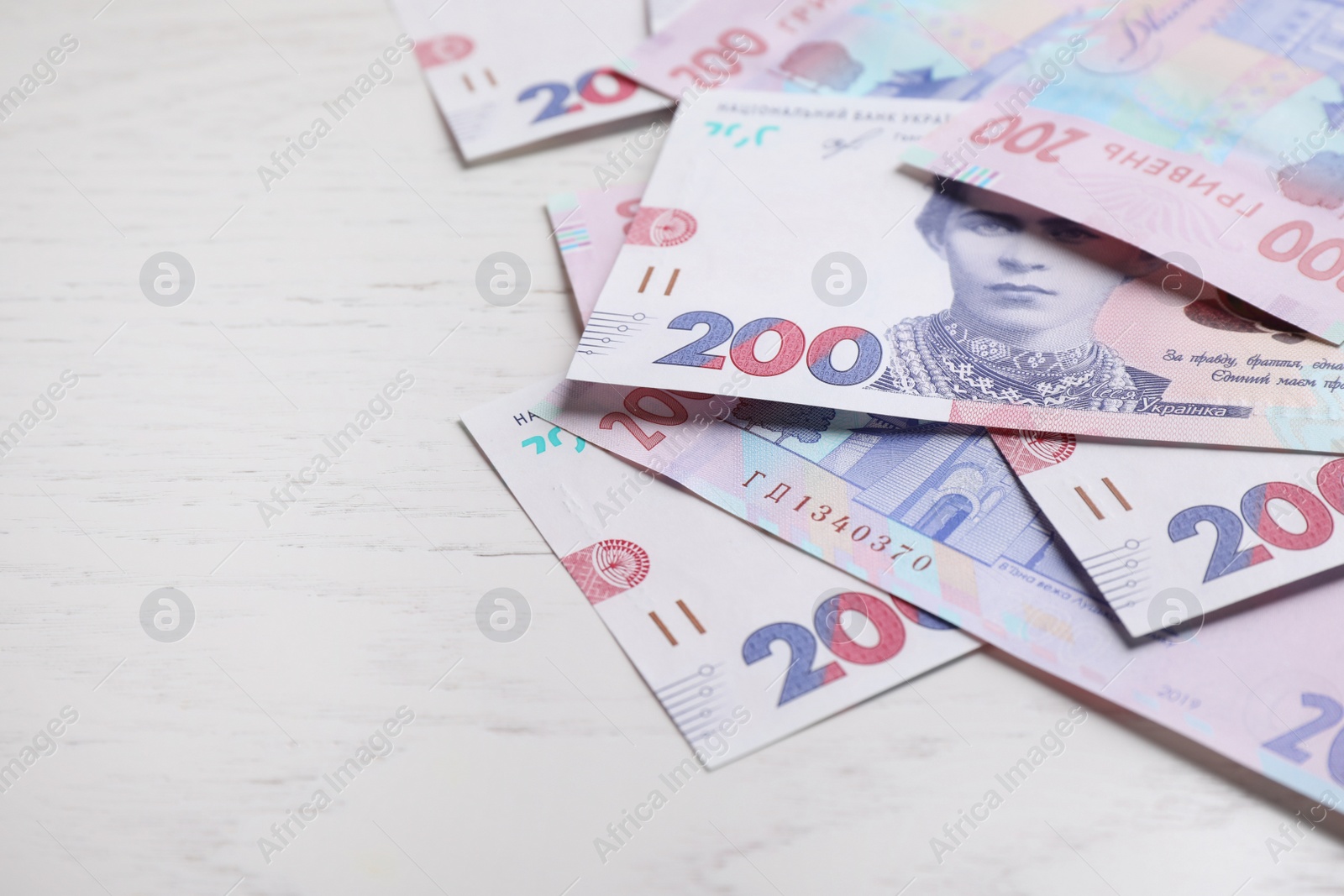 Photo of Ukrainian money on white wooden background, closeup. Space for text