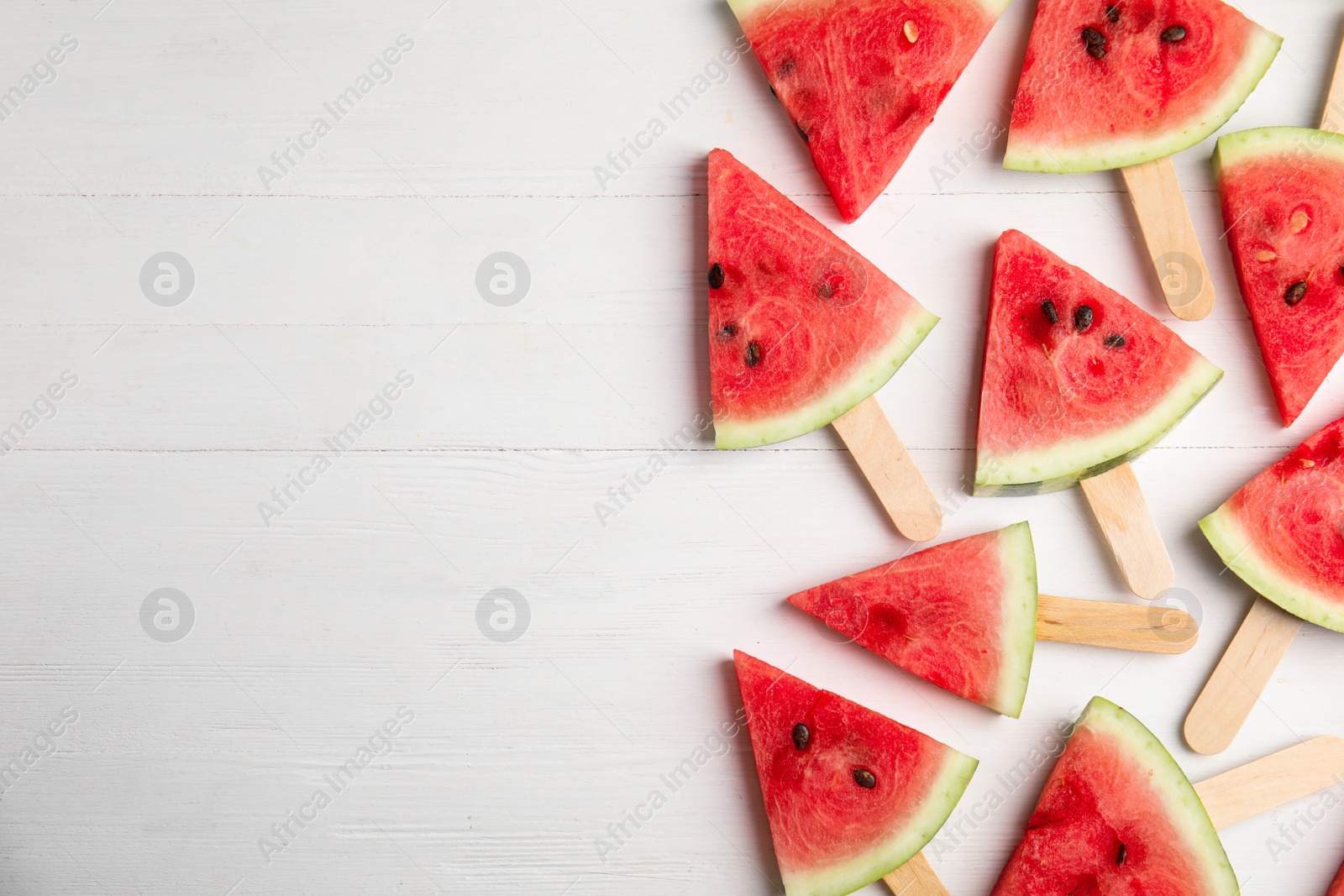 Photo of Slices of ripe watermelon on white wooden table, flat lay. Space for text