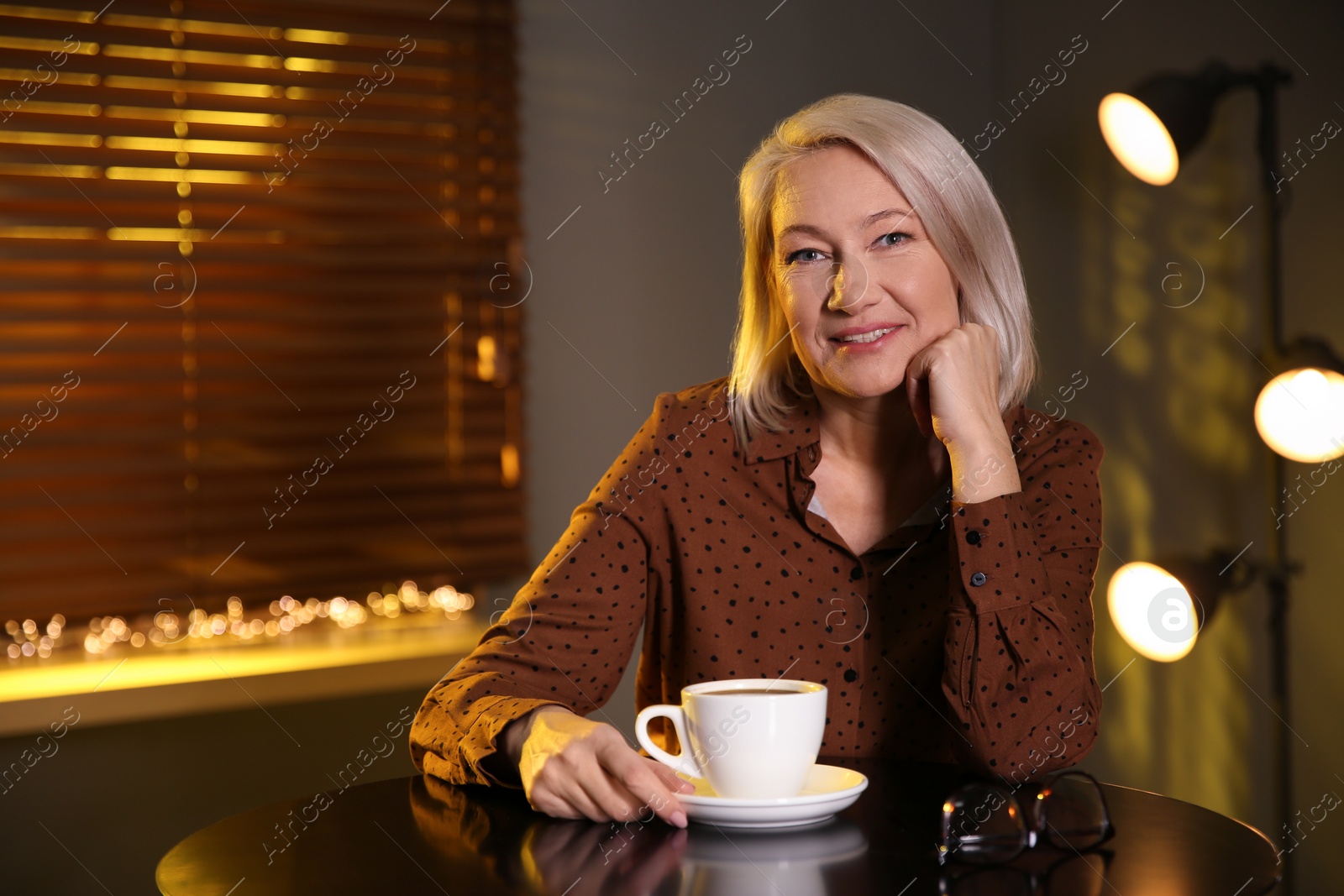 Photo of Beautiful mature woman with cup of coffee indoors. Space for text