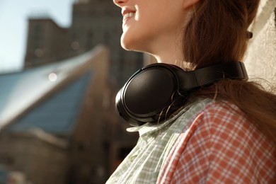 Photo of Smiling woman with headphones outdoors, closeup. Space for text
