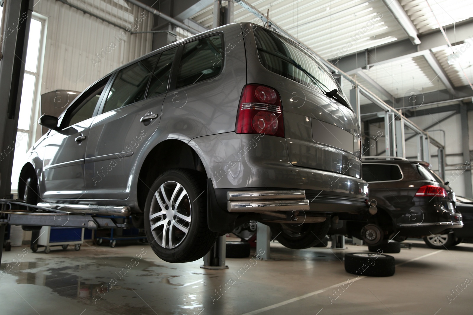 Photo of Modern car on hydraulic lift at automobile repair shop