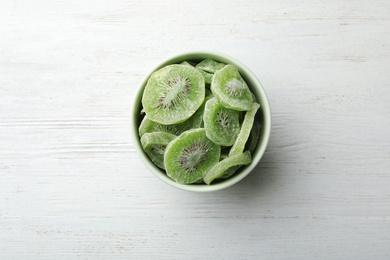 Photo of Bowl with slices of kiwi on wooden background, top view. Dried fruit as healthy food