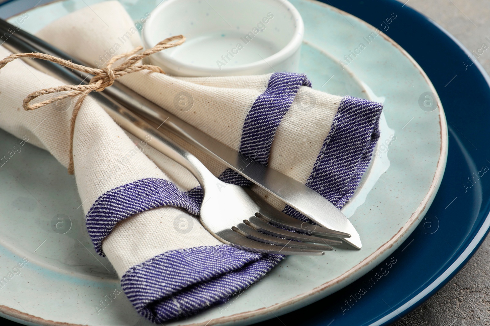 Photo of Stylish setting with cutlery, plates, bowl and napkin on grey table, closeup
