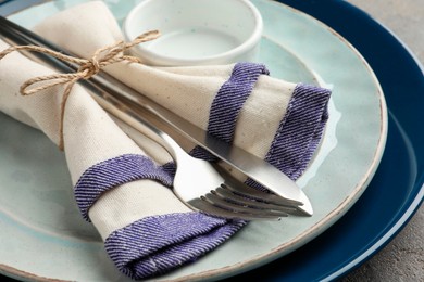 Stylish setting with cutlery, plates, bowl and napkin on grey table, closeup