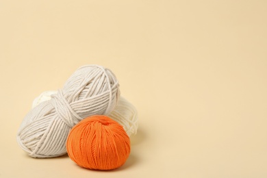 Soft woolen yarns on beige background, space for text