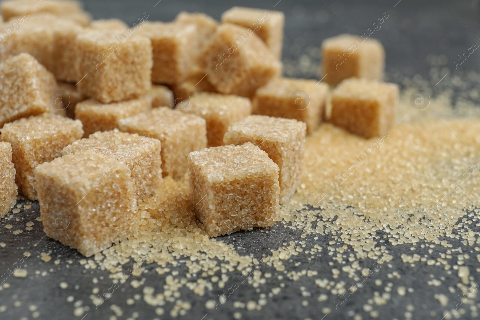 Photo of Brown sugar cubes on grey table, closeup