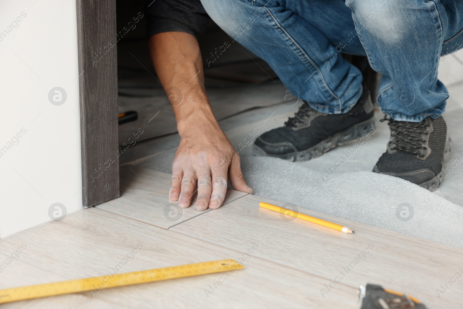 Photo of Worker installing new laminate flooring in room, closeup