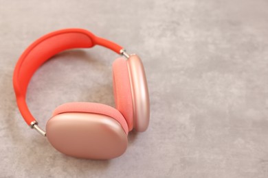 Stylish pink headphones on light grey table, closeup. Space for text