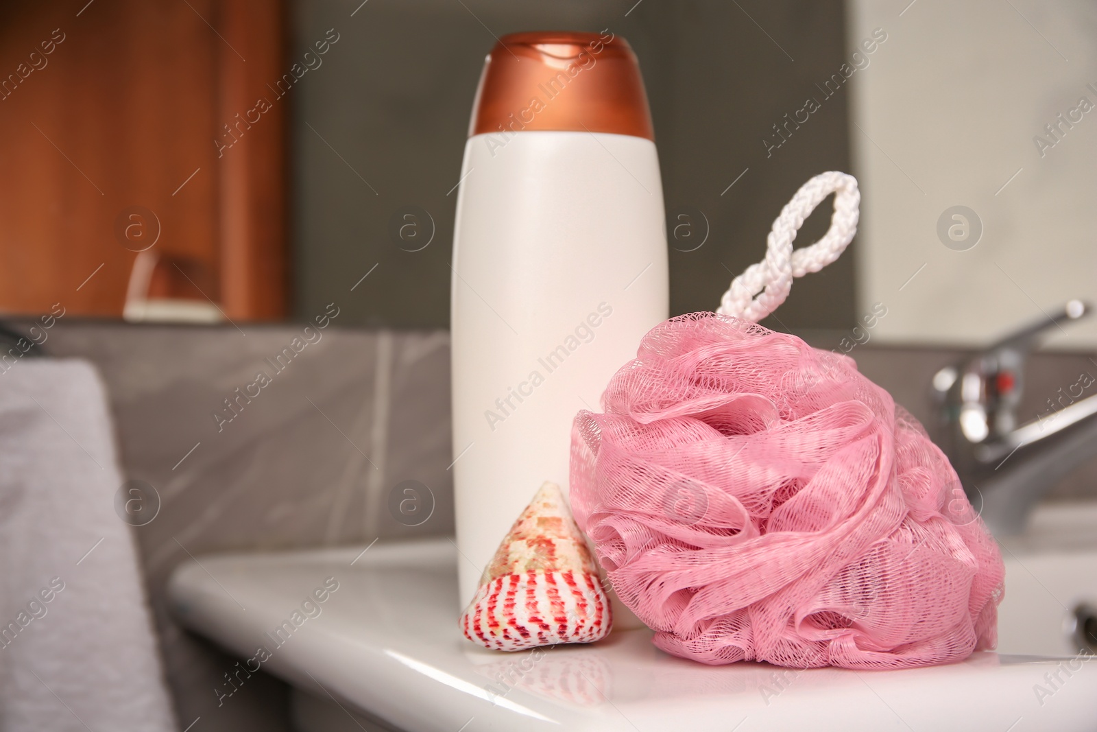 Photo of Pink sponge, seashell and shower gel bottle on washbasin in bathroom, closeup. Space for text