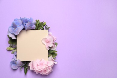 Photo of Beautiful hortensia flowers and blank card on violet background, flat lay. Space for text